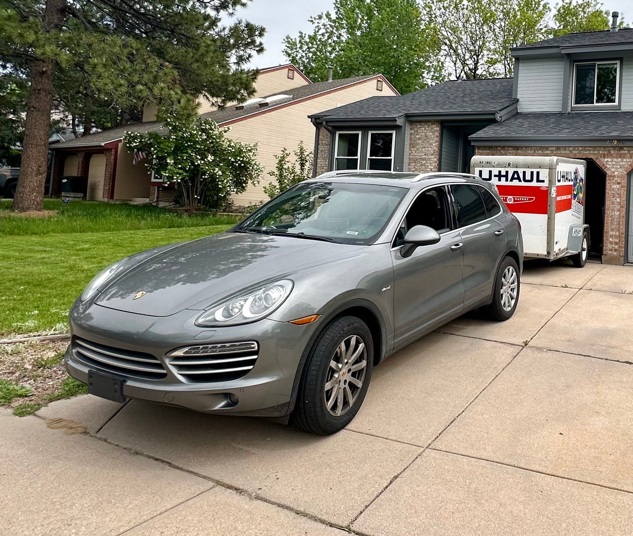Porsche Cayenne in front of a house pulling a U-Haul trailer