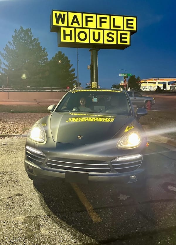 Porsche Cayenne in front of a lit up Waffle House sign at night